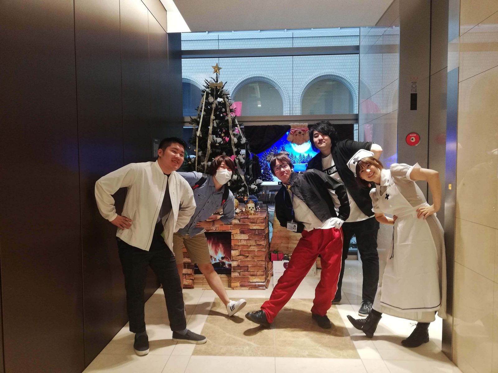 クリスマスツリーの前でポーズをとる学生たち